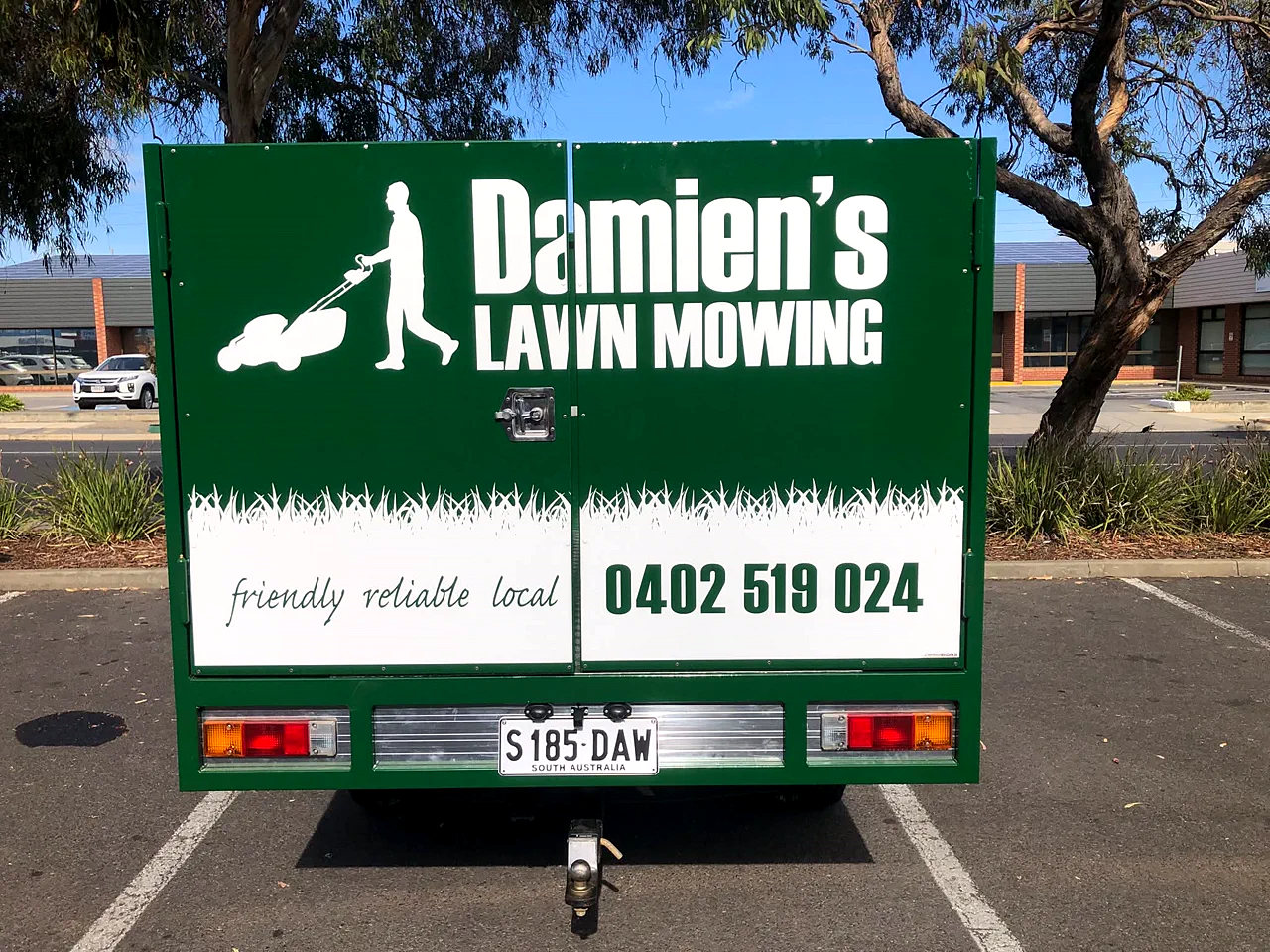 Damien's Lawn Mowing trailer with services and phone number